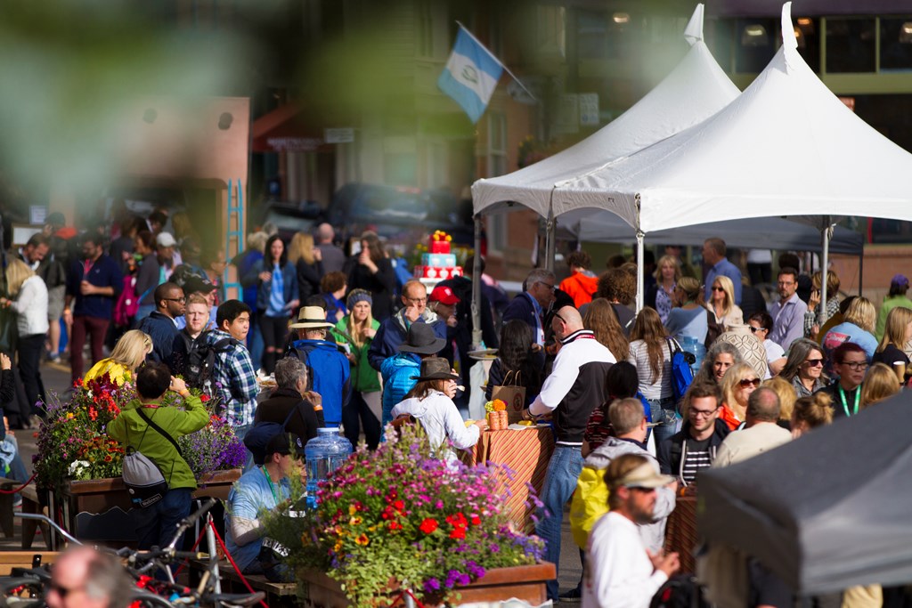 A crowd of people having a good time on a sunny day at an outdoor festival.